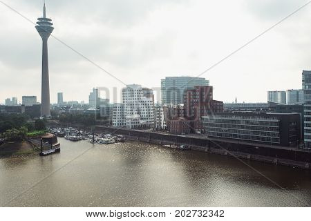 DUSSELDORF, GERMANY - June, 2017: Neuer Zollhof complex designed by Frank Gehry architects with television tower on the waterfront of the Media Harbour in Dusseldorf