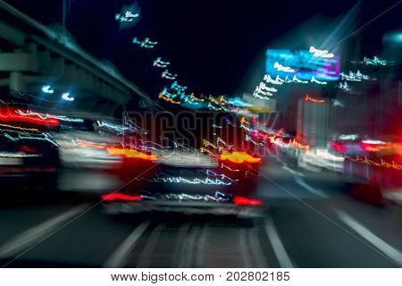 Fast driving traffic at night, blue colors. Abstract blurred background of urban moving car with blur bright brake lights at night. Auto, city street lights and speed. Selective focus
