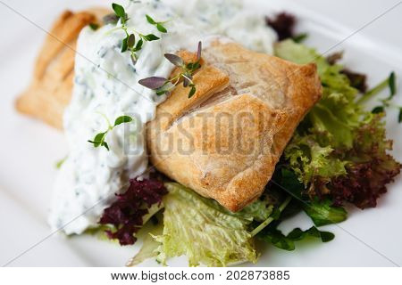 Traditional russian pie - coulibiac. Baked puff pastry filled with smoked salmon, served with sour cream sauce