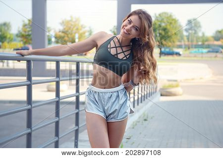 Long Haired Sporty Girl In A Stylish Silver Colored Shorts And Dark Green T-shirt Is Exercising On A