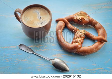 Cup of coffee with coffee beans and pretzel , coffee time