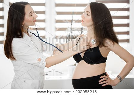 female medicine doctor holding stethoscope to pregnant woman standing for encouragement, empathy, cheering, support, medical examination. New life of abortion concept