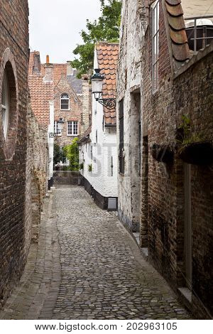 One of the many narrow alleys in the city of Bruges on a cloudy day.