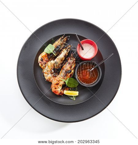 Teppanyaki Japanese and Korean Grill Food - 6/8 Shrimp Grill with fresh herbs and sauces on black plate. Top View