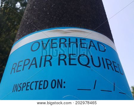 a street light with overhead repair required sign