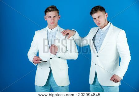 Man holding bank card with black magnetic stripe. Two businessman wearing white jackets on blue background. Banking and saving. Ecash and money. Business and technology concept.