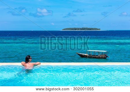 one caucasian woman enjoying vacations  sunbathing on a infinity swimming pool by the seaside looking at the idian ocean Muyuni  in Unguja aka Zanzibar Island Tanzania East Africa