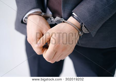 Close-up Of Handcuffed Male Arms In Bracelets. Criminal Wearing Expensive Classy Suit. Arrested Brib