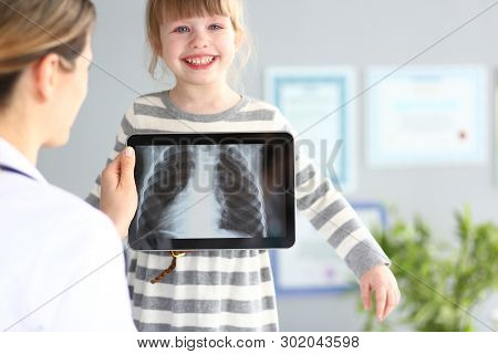 Female Doctor Examining Little Girl With Ultra Modern Scanning Tablet Pc Device Closeup