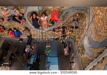 Melbourne, Australia - March 17, 2018: Visitors Resting On The Hand Tufted Wool Rug Entitled Santa C