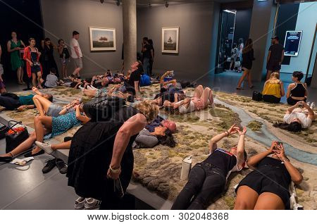 Melbourne, Australia - March 17, 2018: Visitors Resting On The Hand Tufted Wool Rug Entitled Santa C