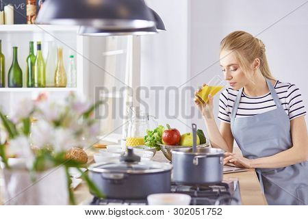 The Girl At The Table In The Kitchen With A Glass Of Orange Jui