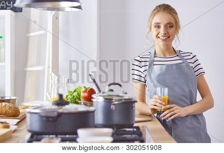 The Girl At The Table In The Kitchen With A Glass Of Orange Jui
