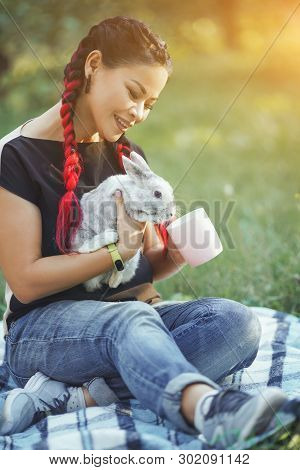 Pretty Asian Girl With Hair Braiding Huggs A Rabbit On Beautiful Forest Glade Taking Care Of Her Pet