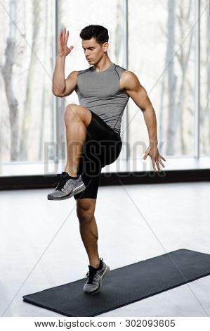 Fit, Athletic Male Model In Sportswear Doing Strength Exercise With Knee Up In Gym, Isolated On A Bi