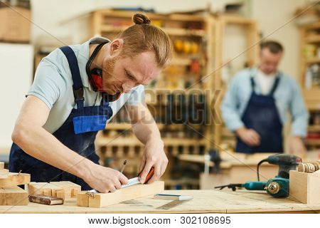 Portrait Of Contemporary Carpenter Working With Wood Standing At Tables In Workshop, Copy Space