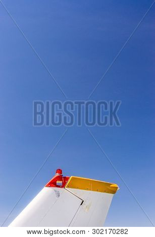 Tail Fin, Rudder And Beacon Lights, Small Single Engine Airplane With Old Paint And Bright Blue Sky.