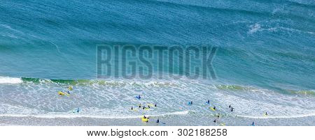 Surfers In The Waves Off Mawgan Porth Beach, Cornwall, Uk