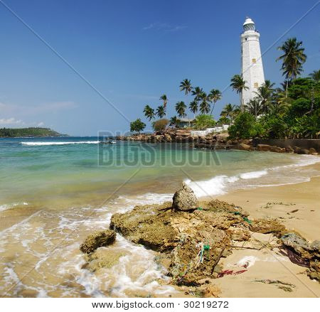 Bellissimo faro bianco Dondra Head, il capo sud dello Sri Lanka - visto dalla spiaggia. Il li
