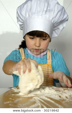 Bambina cucinare una pizza in una cucina.Ragazzino in una cucina.