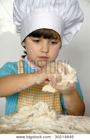 Bambina cucinare una pizza in una cucina.Ragazzino in una cucina.