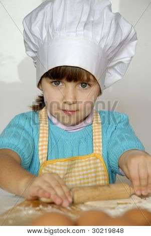 Bambina cucinare una pizza in una cucina.Ragazzino in una cucina.