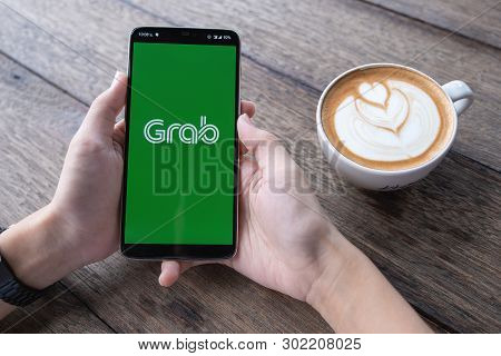 Chiang Mai,thailand - May 11, 2019 : A Man Hand Holding Grab App Showing On Oneplus 6 With Computer 