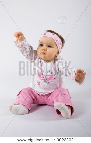 Jeden rok stary słodkie dziecko dziewczynka próbuje złapać baniek mydlanych.