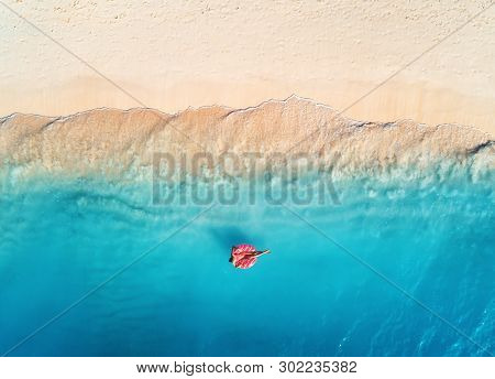 Aerial View Of A Young Woman Swimming With The Donut Swim Ring In The Clear Blue Sea With Waves At S