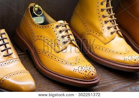 Tan full grain leather brogues shoes set on wooden display in in men shoes boutique store.