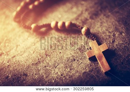 Wooden rosary with cross on stone background. Christian religion. Catholic faith. Prayer.