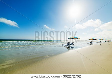 Beach Chairs And Parasols Under A Shining Sun In Daytona Beach. Florida, Usa