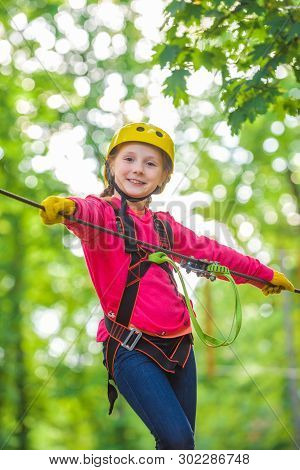 Cute School Child Boy Enjoying A Sunny Day In A Climbing Adventure Activity Park. Artworks Depict Ga