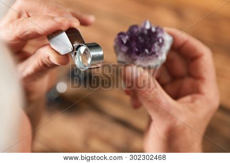 Male Jeweler Evaluating Semi Precious Gemstone At Table In Workshop, Closeup