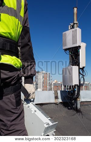 Professional Industrial Climber   In Helmet And Uniform Holds Telecomunication Equipment In His Hand