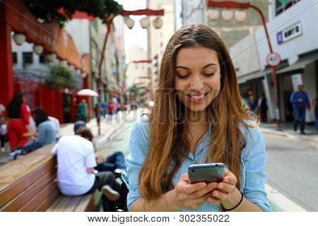 Portrait Of A Smiling Young Woman Walking In The Sao Paulo City With Cellphone, Brazil