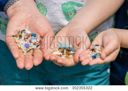 Family Of Mother And Children Holding And Showing Small Tiny Harmful Plastic Beads Collected On The 