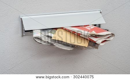 Newspapers And A Letter In A Mail Slot