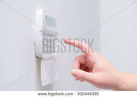 Woman Hand Entering Alarm System Password Of An Apartment, House Of Business Office. Surveillance An