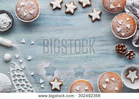 Top View Of The Table With Sugar-sprinkled Muffins, Fondant Icing And Christmas Star Cookies On Blue