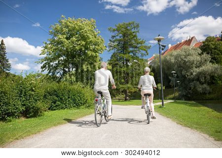 active old age, people and lifestyle concept - happy senior couple riding bicycles at toom park in summer city of tallinn, estonia