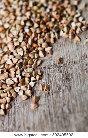 Fresh green dry buckwheat seads closeup on rustic wooden background. Buckwheat texture.