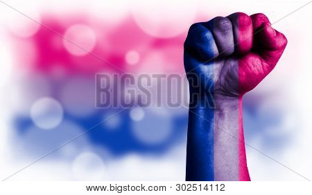 Flag Of Bisexual Painted On Male Fist, Strength, Power, Concept Of Conflict. On A Blurred Background