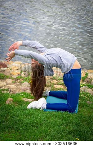 Young Girl Goes In For Sports In Nature. Healthy Lifestyle.flaxible Child Doing Joga Poses Bridge St