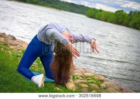 Young Girl Goes In For Sports In Nature. Healthy Lifestyle.flaxible Child Doing Joga Poses Bridge St