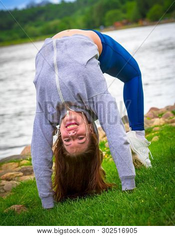 Young Girl Goes In For Sports In Nature. Healthy Lifestyle.flaxible Child Doing Joga Poses Bridge St