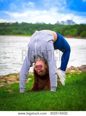 Young Girl Goes In For Sports In Nature. Healthy Lifestyle.flaxible Child Doing Joga Poses Bridge St