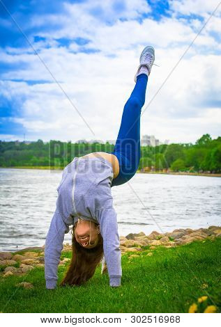 Young Girl Goes In For Sports In Nature. Healthy Lifestyle.flaxible Child Doing Joga Poses Bridge St