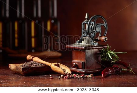 Vintage Pepper Mill With Various Peppers And Spices. Old Pepper Mill With Cooking Utensils, Bottles 