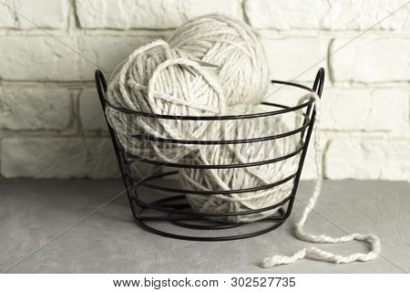 Wool Yarn In Coils And Baals Of Wool With Knitting Needles In Basket